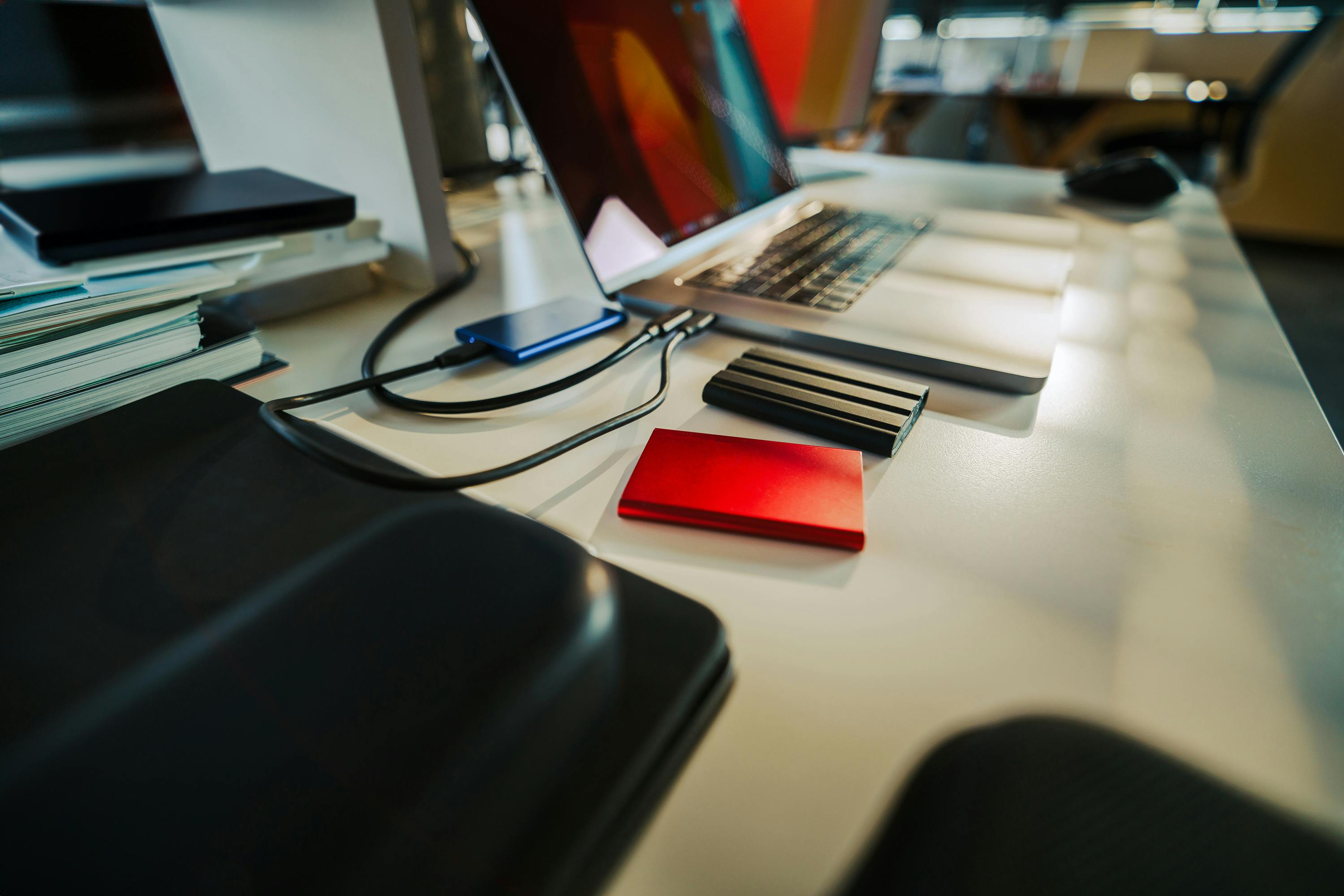Laptop kerja dengan beberapa storage eksternal untuk backup dan pemulihan data bisnis.
